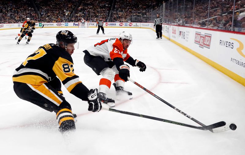 Feb 25, 2024; Pittsburgh, Pennsylvania, USA;  Pittsburgh Penguins center Sidney Crosby (87) and Philadelphia Flyers left wing Noah Cates (27) reach for a loose puck during the third period at PPG Paints Arena.  Pittsburgh won 7-6. Mandatory Credit: Charles LeClaire-USA TODAY Sports