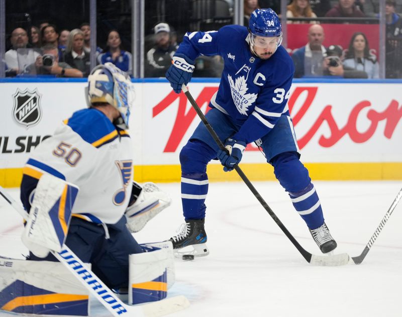 Oct 24, 2024; Toronto, Ontario, CAN; Toronto Maple Leafs forward Auston Matthews (34) can't control a pass in front of St. Louis Blues goaltender Jordan Binnington (50) during the first period at Scotiabank Arena. Mandatory Credit: John E. Sokolowski-Imagn Images