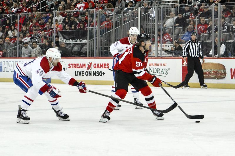 Feb 24, 2024; Newark, New Jersey, USA; New Jersey Devils center Dawson Mercer (91) skates with the puck while being defended by Montreal Canadiens right wing Joel Armia (40) during the second period at Prudential Center. Mandatory Credit: John Jones-USA TODAY Sports