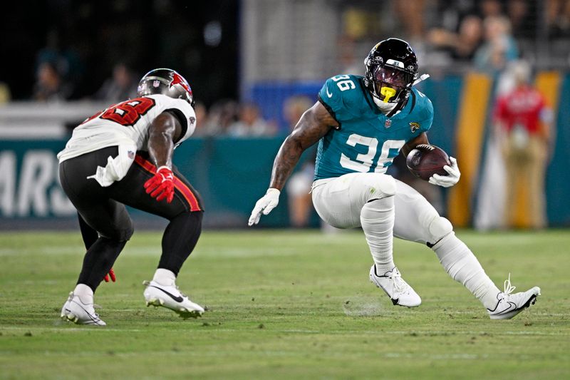 Jacksonville Jaguars running back Jalen Jackson (36) looks for a way around Tampa Bay Buccaneers safety Rashad Wisdom, left, during the second half of an NFL preseason football game, Saturday, Aug. 17, 2024, in Jacksonville, Fla. (AP Photo/Phelan M. Ebenhack)