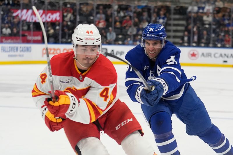 Oct 28, 2025; Toronto, Ontario, CAN; Toronto Maple Leafs forward John Tavares (91) tries to slow up Calgary Flames defenseman Joel Hanley (44) during the first period at Scotiabank Arena. Mandatory Credit: John E. Sokolowski-Imagn Images