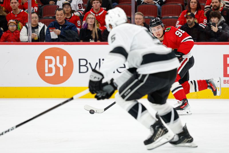 Oct 26, 2025; Chicago, Illinois, USA; Chicago Blackhawks center Connor Bedard (98) passes the puck against Los Angeles Kings defenseman Cody Ceci (5) during the first period at United Center. Mandatory Credit: Kamil Krzaczynski-Imagn Images