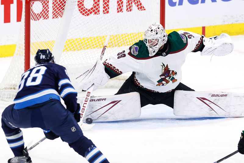 Feb 25, 2024; Winnipeg, Manitoba, CAN; Arizona Coyotes goaltender Connor Ingram (39) makes a pad save on a Winnipeg Jets defenseman Nate Schmidt (88) shot in the third period at Canada Life Centre. Mandatory Credit: James Carey Lauder-USA TODAY Sports