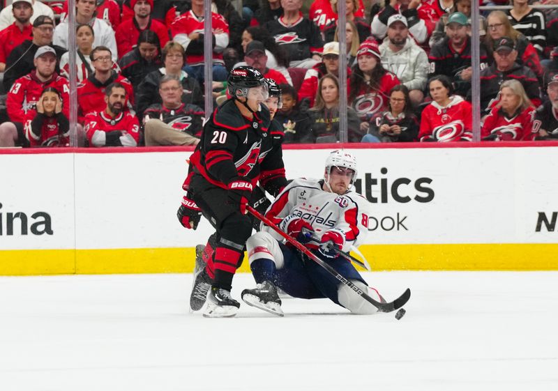 Nov 3, 2024; Raleigh, North Carolina, USA;  Washington Capitals left wing Pierre-Luc Dubois (80) clears the puck away from Carolina Hurricanes center Sebastian Aho (20) during the second period at Lenovo Center. Mandatory Credit: James Guillory-Imagn Images