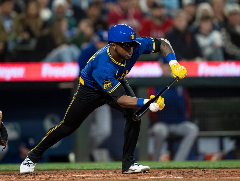 Jun 14, 2024; Seattle, Washington, USA; Seattle Mariners left fielder Victor Robles (10) hits a butn single during the fourth inning against the Texas Rangers at T-Mobile Park. Mandatory Credit: Stephen Brashear-USA TODAY Sports