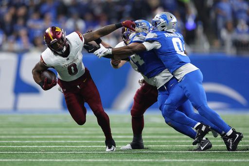 Washington Commanders running back Brian Robinson Jr. (8) runs the ball as Detroit Lions linebacker Alex Anzalone (34) and cornerback Terrion Arnold (0) try to make the tackle during the second half of an NFL football divisional playoff game, Saturday, Jan. 18, 2025, in Detroit. (AP Photo/Mike Mulholland)