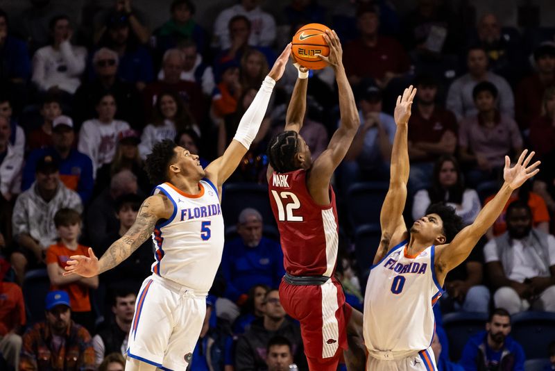 Jan 13, 2024; Gainesville, Florida, USA; Arkansas Razorbacks guard Tramon Mark (12) shoots the ball against Florida Gators guard Will Richard (5) and guard Zyon Pullin (0) during the second half at Exactech Arena at the Stephen C. O'Connell Center. Mandatory Credit: Matt Pendleton-USA TODAY Sports