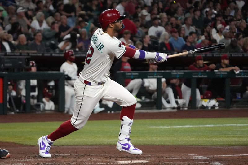 Apr 27, 2025; Phoenix, Arizona, USA; Arizona Diamondbacks outfielder Lourdes Gurriel Jr. (12) hits an RBI sacrifice fly out against the Atlanta Braves in the second inning at Chase Field. Mandatory Credit: Rick Scuteri-Imagn Images