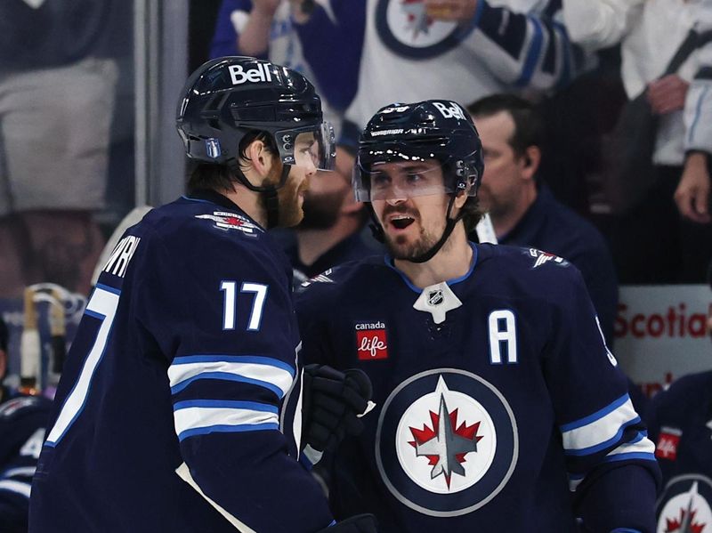 May 9, 2025; Winnipeg, Manitoba, CAN; Winnipeg Jets center Adam Lowry (17) celebrates his goal against the Dallas Stars with Winnipeg Jets center Mark Scheifele (55) in the second period in game two of the second round of the 2025 Stanley Cup Playoffs at Canada Life Centre. Mandatory Credit: James Carey Lauder-Imagn Images