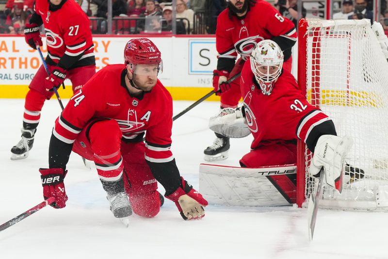 Jan 16, 2026; Raleigh, North Carolina, USA;  Carolina Hurricanes goaltender Brandon Bussi (32) and Carolina Hurricanes defenseman Jaccob Slavin (74) watch the play against the Florida Panthers during the second period at Lenovo Center. Mandatory Credit: James Guillory-Imagn Images
