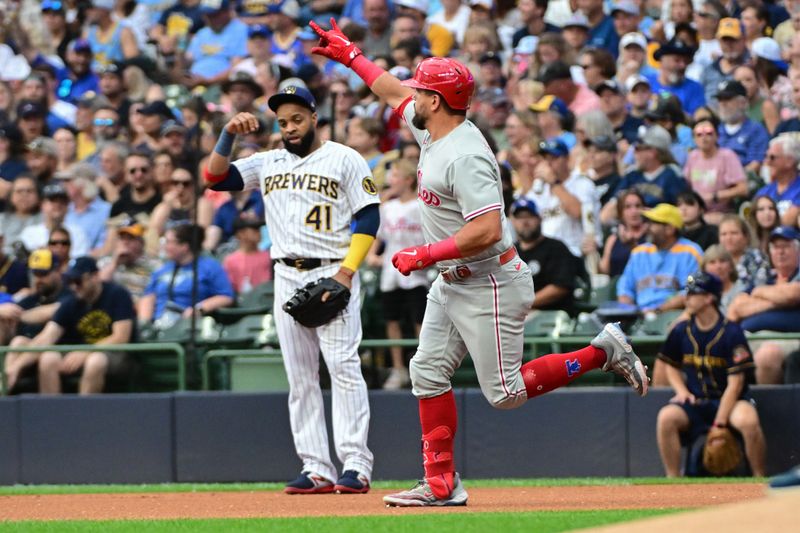 Sep 2, 2023; Milwaukee, Wisconsin, USA; Philadelphia Phillies left fielder Kyle Schwarber (12) reacts after hitting a solo home run in the first inning as Milwaukee Brewers first baseman Carlos Santana (41) looks on at American Family Field. Mandatory Credit: Benny Sieu-USA TODAY Sports