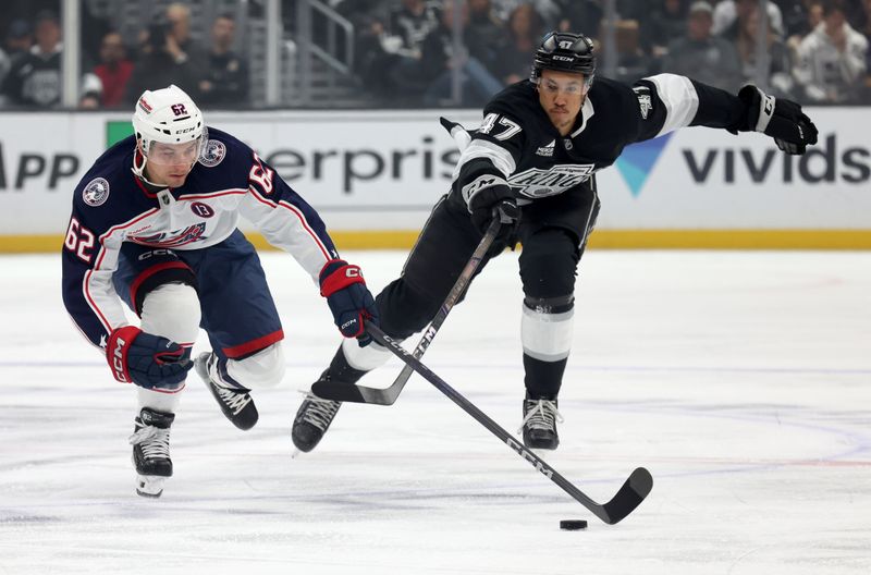 Nov 9, 2024; Los Angeles, California, USA; Columbus Blue Jackets right wing Kevin Labanc (62) and Los Angeles Kings left wing Andre Lee (47) chase a loose puck during the first period at Crypto.com Arena. Mandatory Credit: Jason Parkhurst-Imagn Images