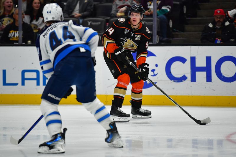 Jan 5, 2024; Anaheim, California, USA; Anaheim Ducks defenseman Pavel Mintyukov (34) moves the puck against Winnipeg Jets defenseman Josh Morrissey (44) during the second period at Honda Center. Mandatory Credit: Gary A. Vasquez-USA TODAY Sports