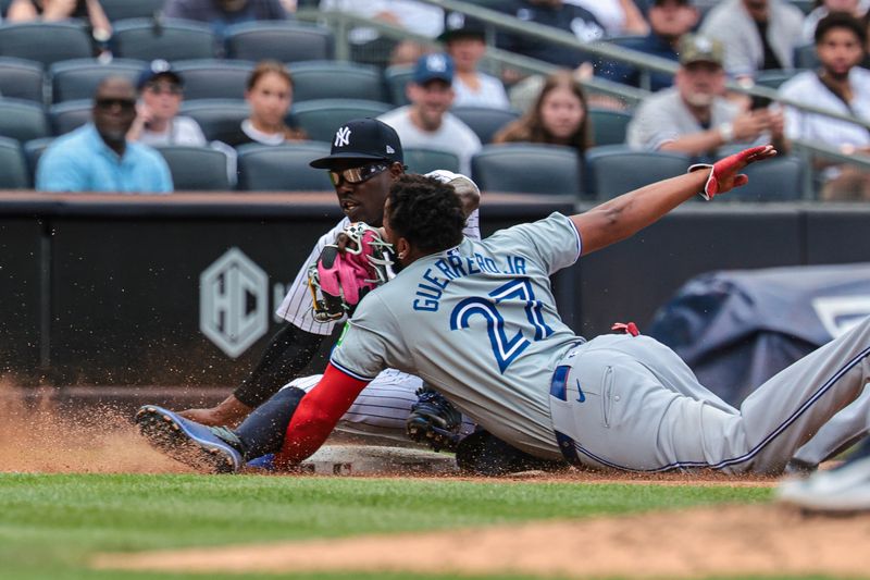 Aug 4, 2024; Bronx, New York, USA;  New York Yankees third baseman Jazz Chisholm Jr. (13) tags out Toronto Blue Jays first baseman Vladimir Guerrero Jr. (27) on a steal attempt at third base during the third inning at Yankee Stadium. Mandatory Credit: Vincent Carchietta-USA TODAY Sports