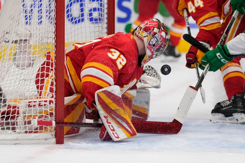 Mar 17, 2025; Toronto, Ontario, CAN; Calgary Flames goaltender Dustin Wolf (32) battles to control a rebound against the Toronto Maple Leafs during the first period at Scotiabank Arena. Mandatory Credit: John E. Sokolowski-Imagn Images
