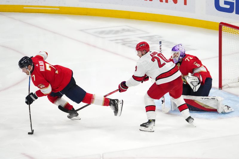 Nov 10, 2023; Sunrise, Florida, USA; Florida Panthers defenseman Dmitry Kulikov (7) clears the puck while being tripped by Carolina Hurricanes center Sebastian Aho (20) during the third period at Amerant Bank Arena. Mandatory Credit: Jasen Vinlove-USA TODAY Sports