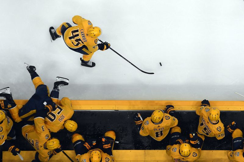 Dec 27, 2023; Nashville, Tennessee, USA; Nashville Predators defenseman Alexandre Carrier (45) plays the puck as defenseman Roman Josi (59) jumps into the bench to avoid a penalty during the second period against the Carolina Hurricanes at Bridgestone Arena. Mandatory Credit: Christopher Hanewinckel-USA TODAY Sports