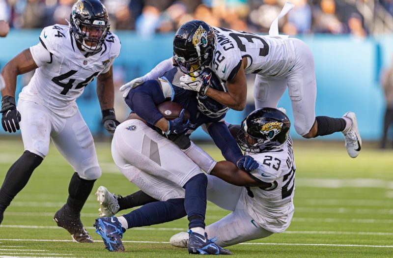 Tennessee Titans running back Derrick Henry (22) is tackled by Jacksonville Jaguars cornerback Tyson Campbell (32) and linebacker Foyesade Oluokun (23) during their NFL football game Sunday, Jan. 7, 2024, in Nashville, Tenn. (AP Photo/Wade Payne)