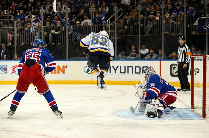 Nov 25, 2024; New York, New York, USA; St. Louis Blues left wing Jake Neighbours (63) jumps to avoid the puck while New York Rangers defenseman Ryan Lindgren (55) and goalie Igor Shesterkin (31) defend during the third period at Madison Square Garden. Mandatory Credit: Danny Wild-Imagn Images