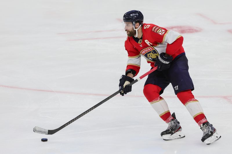 Jan 13, 2024; Sunrise, Florida, USA; Florida Panthers defenseman Aaron Ekblad (5) moves the puck against the New Jersey Devils during the third period at Amerant Bank Arena. Mandatory Credit: Sam Navarro-USA TODAY Sports