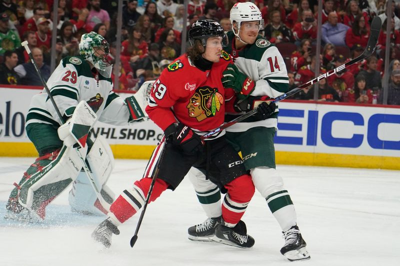 Oct 4, 2024; Chicago, Illinois, USA; Chicago Blackhawks left wing Tyler Bertuzzi (59) and Minnesota Wild center Joel Eriksson Ek (14) tie up during the first period at United Center. Mandatory Credit: David Banks-Imagn Images