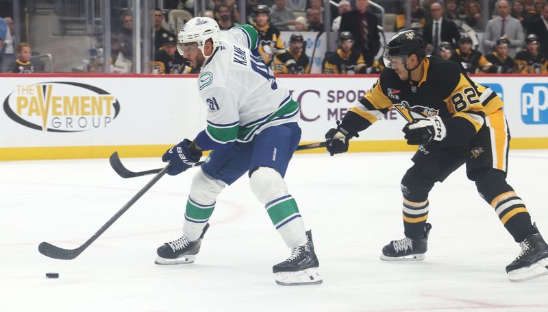 Oct 21, 2025; Pittsburgh, Pennsylvania, USA;  Vancouver Canucks left wing Evander Kane (91) skates with the puck ahead of Pittsburgh Penguins defenseman Caleb Jones (82) during the first period at PPG Paints Arena. Mandatory Credit: Charles LeClaire-Imagn Images
