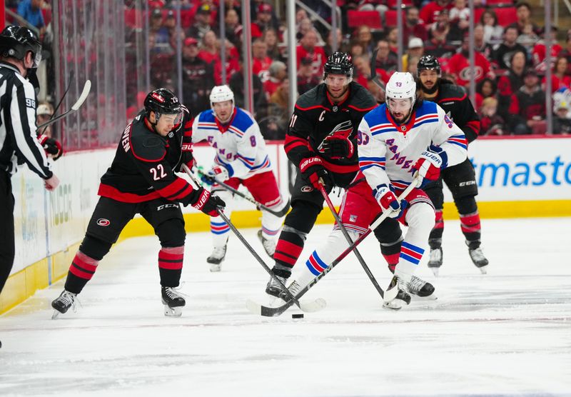 Apr 12, 2025; Raleigh, North Carolina, USA;  New York Rangers center Mika Zibanejad (93) skates with the puck against Carolina Hurricanes center Logan Stankoven (22) and center Jordan Staal (11) during the first period at Lenovo Center. Mandatory Credit: James Guillory-Imagn Images