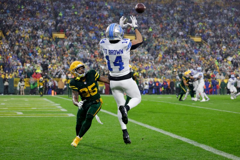 Detroit Lions wide receiver Amon-Ra St. Brown (14) catches a touchdown past Green Bay Packers cornerback Keisean Nixon (25) during the first half of an NFL football game Sunday, Nov. 3, 2024, in Green Bay, Wis. (AP Photo/Matt Ludtke)