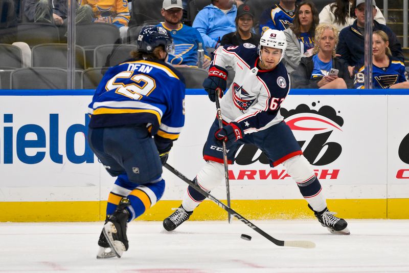 Oct 1, 2024; St. Louis, Missouri, USA;  Columbus Blue Jackets forward Jake Gaudet (63) controls the puck as St. Louis Blues center Zach Dean (52) defends during the third period at Enterprise Center. Mandatory Credit: Jeff Curry-Imagn Images