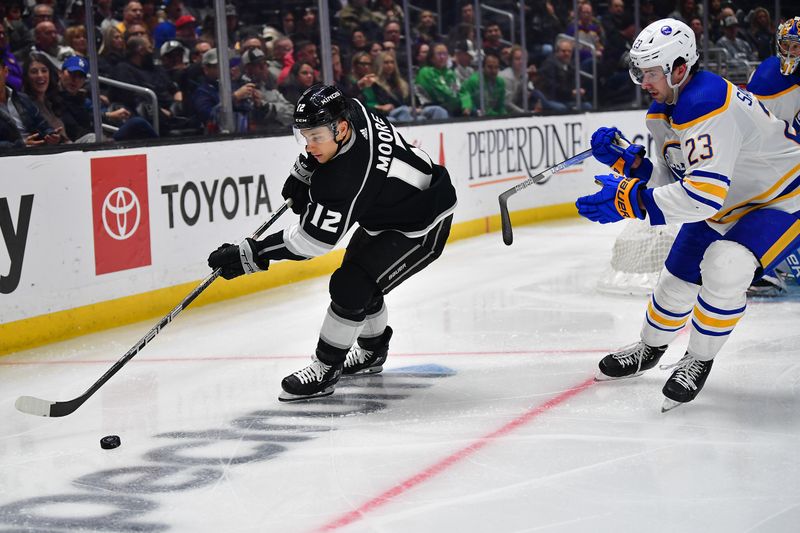 Feb 13, 2023; Los Angeles, California, USA; Los Angeles Kings left wing Trevor Moore (12) moves the puck against Buffalo Sabres defenseman Mattias Samuelsson (23) during the second period at Crypto.com Arena. Mandatory Credit: Gary A. Vasquez-USA TODAY Sports