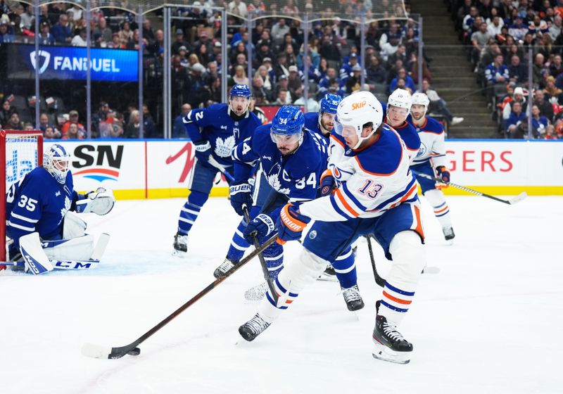 Dec 13, 2025; Toronto, Ontario, CAN; Toronto Maple Leafs center Auston Matthews (34) battles for the puck with Edmonton Oilers center Mattias Janmark (13) during the second period at Scotiabank Arena. Mandatory Credit: Nick Turchiaro-Imagn Images