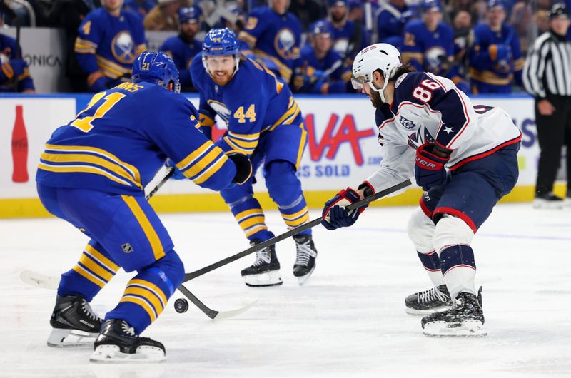 Oct 28, 2025; Buffalo, New York, USA;  Buffalo Sabres defenseman Conor Timmins (21) tries to block a pass by Columbus Blue Jackets right wing Kirill Marchenko (86) during the third period at KeyBank Center. Mandatory Credit: Timothy T. Ludwig-Imagn Images