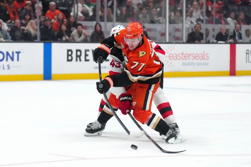 Dec 31, 2024; Anaheim, California, USA; Anaheim Ducks right wing Frank Vatrano (77) shoots the puck against New Jersey Devils defenseman Luke Hughes (43) in the third period at Honda Center. Mandatory Credit: Kirby Lee-Imagn Images