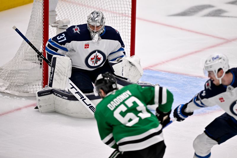 May 17, 2025; Dallas, Texas, USA; Winnipeg Jets goaltender Connor Hellebuyck (37) faces a shot from Dallas Stars right wing Evgenii Dadonov (63) during the first period in game six of the second round of the 2025 Stanley Cup Playoffs at American Airlines Center. Mandatory Credit: Jerome Miron-Imagn Images