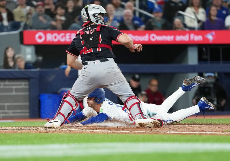 May 3, 2025; Toronto, Ontario, CAN; Toronto Blue Jays pinch hitter Ernie Clement (22) slides into home plate ahead of the tag from Cleveland Guardians catcher Austin Hedges (27) during the fifth inning at Rogers Centre. Mandatory Credit: Nick Turchiaro-Imagn Images