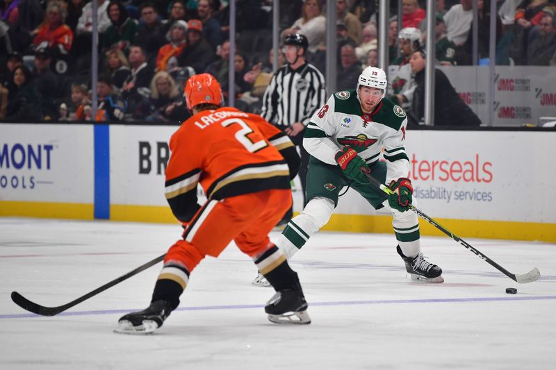 Dec 6, 2024; Anaheim, California, USA; Minnesota Wild center Yakov Trenin (13) moves the puck against Anaheim Ducks defenseman Jackson LaCombe (2) during the third period at Honda Center. Mandatory Credit: Gary A. Vasquez-Imagn Images