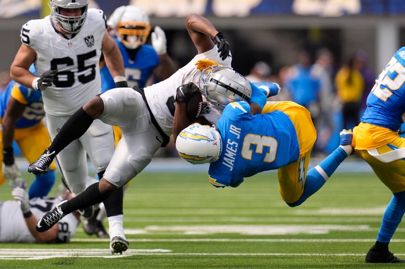 Las Vegas Raiders running back Zamir White, foreground top, is tackled by Los Angeles Chargers safety Derwin James Jr. during the second half of an NFL football game, Sunday, Sept. 8, 2024, in Inglewood, Calif. (AP Photo/Marcio Jose Sanchez)