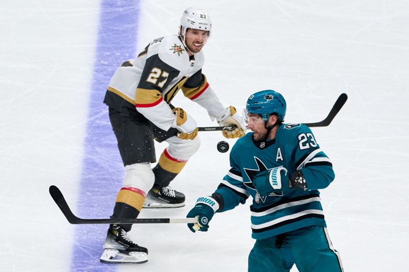 Oct 9, 2025; San Jose, California, USA; San Jose Sharks center Barclay Goodrow (23) and Vegas Golden Knights defenseman Shea Theodore (27) watch a loose puck in the air during the third period at SAP Center at San Jose. Mandatory Credit: Robert Edwards-Imagn Images