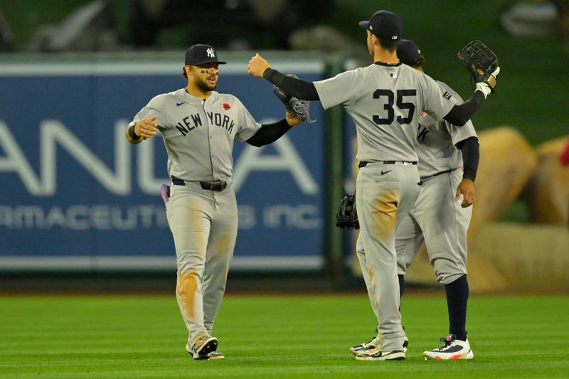 May 26, 2025; Anaheim, California, USA;  New York Yankees left fielder Jasson Dominguez (24), center fielder Trent Grisham (12) and right fielder Cody Bellinger (35) hug after the final out of the ninth inning against the Los Angeles Angels at Angel Stadium. Mandatory Credit: Jayne Kamin-Oncea-Imagn Images
