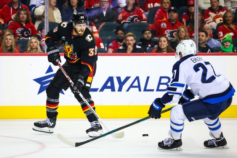 Oct 26, 2024; Calgary, Alberta, CAN; Calgary Flames right wing Anthony Mantha (39) passes the puck in front of Winnipeg Jets left wing Nikolaj Ehlers (27) during the second period at Scotiabank Saddledome. Mandatory Credit: Sergei Belski-Imagn Images