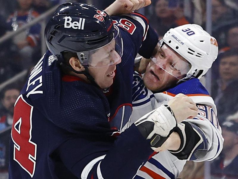 Mar 26, 2024; Winnipeg, Manitoba, CAN; Winnipeg Jets defenseman Logan Stanley (64) and Edmonton Oilers right wing Corey Perry (90) fight in the first period at Canada Life Centre. Mandatory Credit: James Carey Lauder-USA TODAY Sports