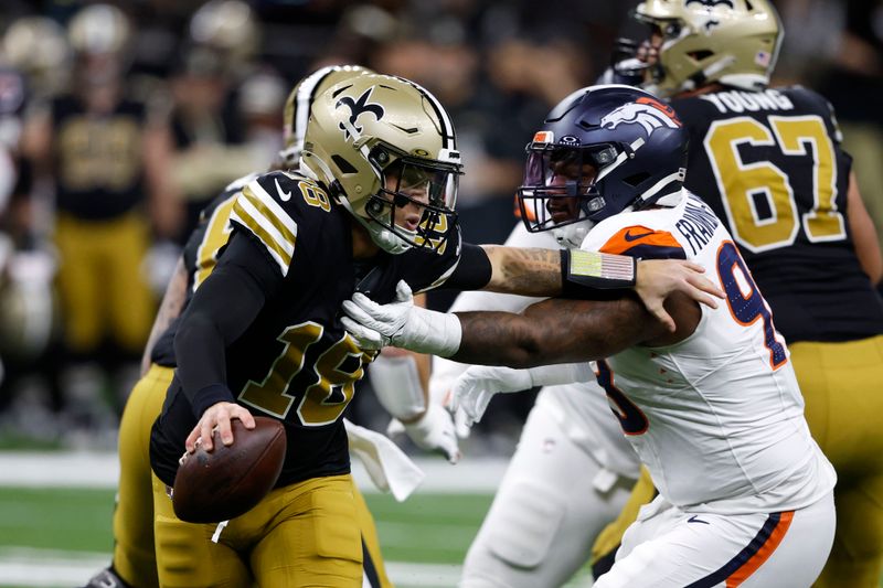 New Orleans Saints quarterback Spencer Rattler (18) runs from Denver Broncos defensive end John Franklin-Myers (98) during the first half of an NFL football game, Thursday, Oct. 17, 2024, in New Orleans. (AP Photo/Butch Dill)