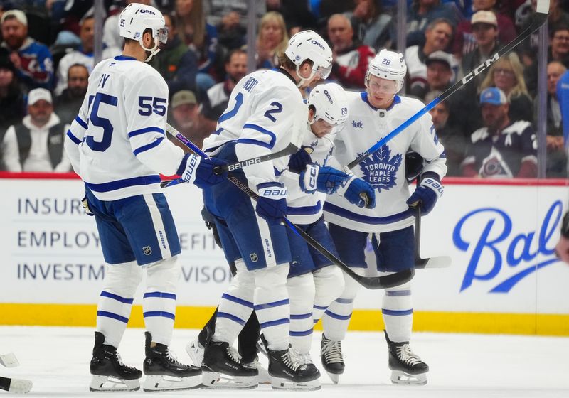 Jan 12, 2026; Denver, Colorado, USA; Toronto Maple Leafs left wing Nicholas Robertson (89) is helped off the ice by defenseman Troy Stecher (28) and defenseman Simon Benoit (2) in the first period against the Colorado Avalanche at Ball Arena. Mandatory Credit: Ron Chenoy-Imagn Images