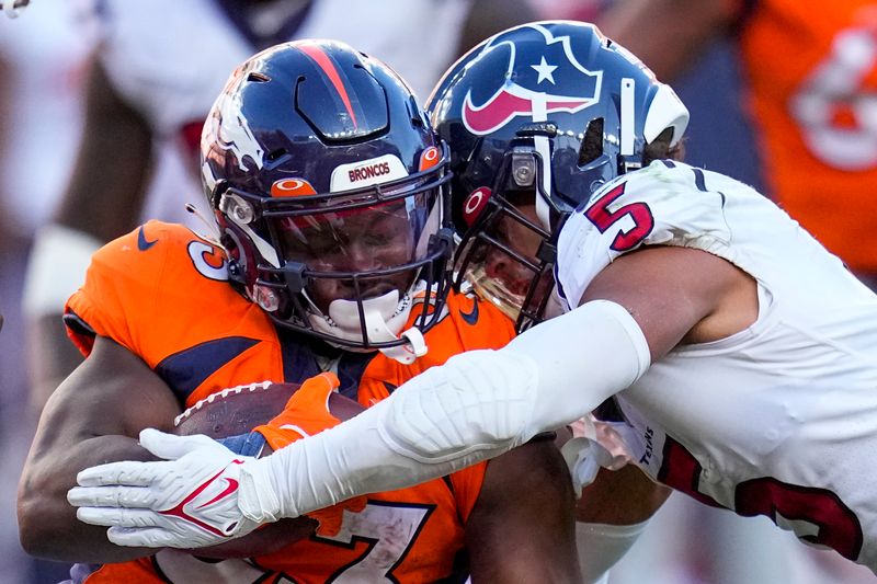 Denver Broncos running back Javonte Williams (33) is tackled by Houston Texans safety Jalen Pitre (5) during an NFL football game Sunday, Sept. 18, 2022, in Denver. (AP Photo/Jack Dempsey)