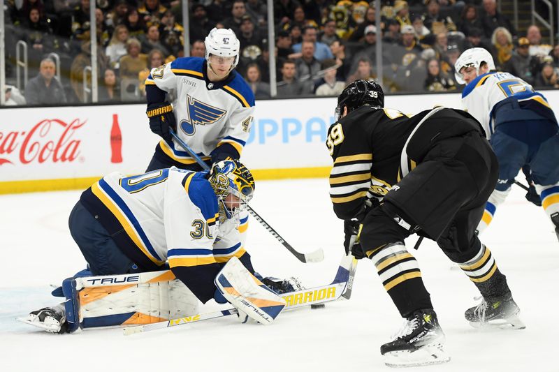 Mar 11, 2024; Boston, Massachusetts, USA;  Boston Bruins center Morgan Geekie (39) tries to free the puck from St. Louis Blues goaltender Joel Hofer (30) during the third period at TD Garden. Mandatory Credit: Bob DeChiara-USA TODAY Sports