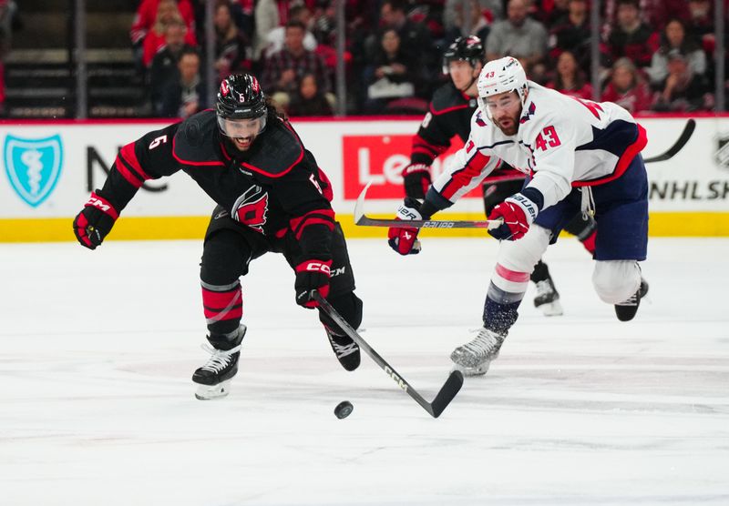 Apr 5, 2024; Raleigh, North Carolina, USA; Carolina Hurricanes defenseman Jalen Chatfield (5) and Washington Capitals right wing Tom Wilson (43) chased after the puck during the first period at PNC Arena. Mandatory Credit: James Guillory-USA TODAY Sports