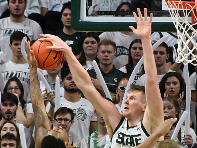 Feb 20, 2024; East Lansing, Michigan, USA;  Michigan State Spartans forward Jaxon Kohler (0) blocks a shot by Iowa Hawkeyes guard Tony Perkins (11) during the second half at Jack Breslin Student Events Center. Mandatory Credit: Dale Young-USA TODAY Sports
