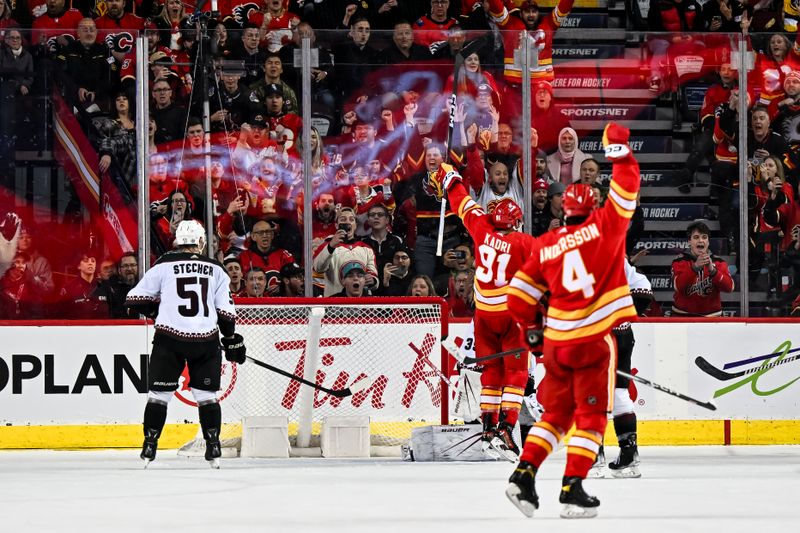 Jan 16, 2024; Calgary, Alberta, CAN; Calgary Flames center Nazem Kadri (91) and defenseman Rasmus Andersson (4) celebrate the game-winning goal by center Yegor Sharangovich (17), not shown, against the Arizona Coyotes during overtime at Scotiabank Saddledome. Mandatory Credit: Brett Holmes-USA TODAY Sports