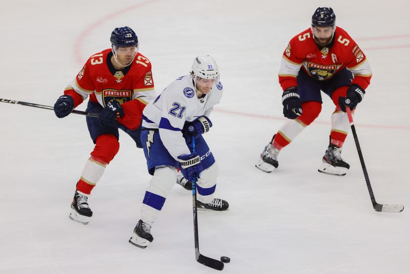 Apr 21, 2024; Sunrise, Florida, USA; Tampa Bay Lightning center Brayden Point (21) moves the puck past Florida Panthers center Sam Reinhart (13) during the third period in game one of the first round of the 2024 Stanley Cup Playoffs at Amerant Bank Arena. Mandatory Credit: Sam Navarro-USA TODAY Sports