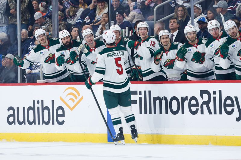 Oct 13, 2024; Winnipeg, Manitoba, CAN;  Minnesota Wild defenseman Jake Middleton (5) is congratulated by his team mates on his goal against the Winnipeg Jets during the first period at Canada Life Centre. Mandatory Credit: Terrence Lee-Imagn Images